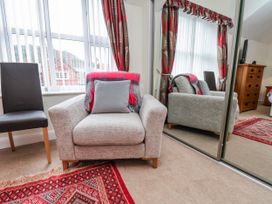 A living room with an armchair and a mirror at 50 West Street Edelweiss in Scarborough