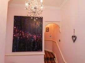A hallway with a chandelier and artwork at 50 West Street Edelweiss, Scarborough