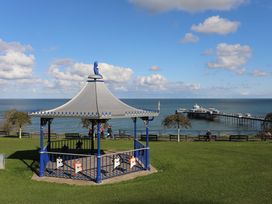 A bandstand by the sea with a pier in the background at The Keep Llandudno