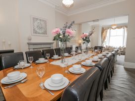 A dining room with a long table set for a meal at The Keep in Llandudno