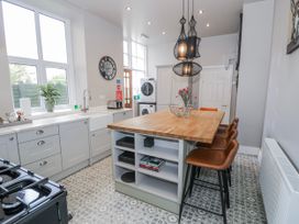 A kitchen with a large countertop and bar stools at The Keep in Llandudno
