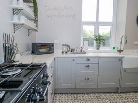 A kitchen with a gas stove and microwave at The Keep in Llandudno