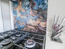 A kitchen with a gas stove and knife block at The Keep in Llandudno