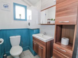 A bathroom with a sink, toilet, and shelving at The Keep in Llandudno