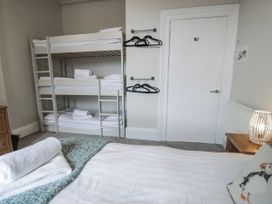 A bedroom with a bunk bed and storage at The Keep in Llandudno
