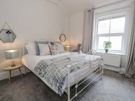 A bedroom with a bed, nightstand, and window at The Keep in Llandudno