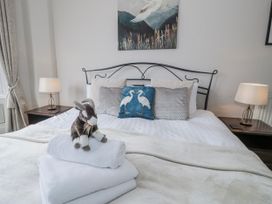 A bedroom with a bed, nightstand, lamp, and towels at The Keep in Llandudno