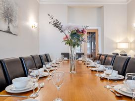 A dining room with a long table set for a meal at The Keep in Llandudno