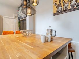 A dining room with a wooden table and kitchenware at The Keep in Llandudno