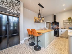 A kitchen with a refrigerator, bar stools, and a kitchen island at The Keep in Llandudno