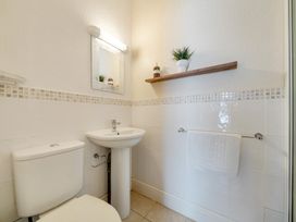 A bathroom with a toilet, sink, and shelf at The Keep in Llandudno