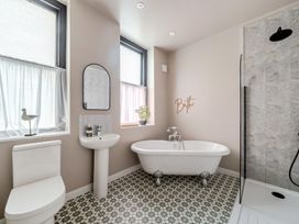 A bathroom with a bathtub, toilet, sink and shower at The Keep in Llandudno