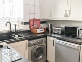 A kitchen corner with a sink toaster microwave kettle washing machine and dishwasher at The White House in Torquay