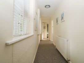 A hallway with carpeted floor windows with blinds on one side radiator and framed pictures on the other at The White House in Torquay