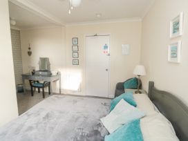 A bedroom with a bed with blue pillows a side table with a lamp a chair a dressing table and a door at The White House in Torquay