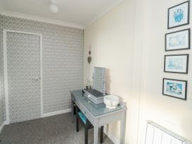 A room with a patterned wallpapered wall door a small table with a mirror and decorative items a chair and framed pictures on the wall at The White House in Torquay