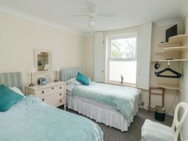 A bedroom with two single beds a window and shelves with hangers at The White House in Torquay