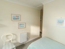 A bedroom corner with a white chair a heater and framed pictures on walls at The White House in Torquay