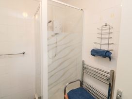 A bathroom with a corner shower enclosure a chrome towel rack and a chair with blue towels at The White House in Torquay