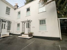A white building exterior with two doors and windows no parking signs and a covered parking area at The White House in Torquay