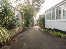 A paved driveway with plants along the sides and a white building with large windows at The White House in Torquay