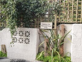 A white textured wall with green plants wooden posts and a parking sign at The White House in Torquay