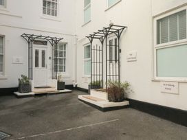 A building entrance with two white doors and black metal awnings with planters and steps at The Link in Torquay