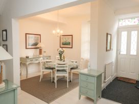 A dining area with a round table set with plates glasses and a vase of flowers near a white front door at The Link in Torquay