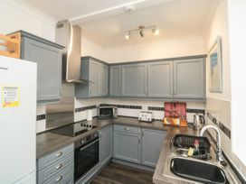 A kitchen with grey cabinets a stove oven microwave toaster kettle and sink at The Link in Torquay