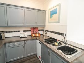 A kitchen with grey cabinets a sink a dishwasher a toaster a microwave and a framed picture on the wall at The Link in Torquay