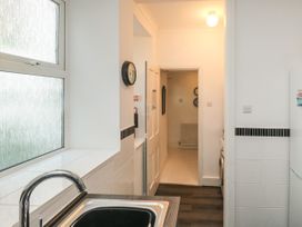 A kitchen area with a sink and faucet by a window looking through a doorway to a hallway at The Link in Torquay