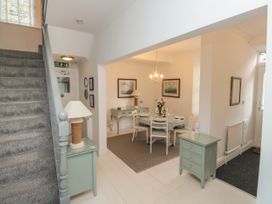 A hallway with stair carpeted stairs a lamp on a small table and a dining area with a table and chairs at The Link in Torquay