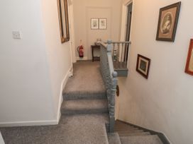 A carpeted staircase and hallway with framed pictures on the walls a table with decorative items and a fire extinguisher at The Link in Torquay