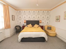 A bedroom with a bed with yellow and white bedding two bedside tables with lamps a yellow chaise lounge and a chair at The Link in Torquay