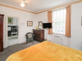 A bedroom with a yellow blanket on the bed a wooden dresser with a mirror a chair and a window with curtains at The Link in Torquay