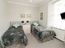 A bedroom with two single beds a bedside table with lamps and a wall-mounted television at The Link in Torquay