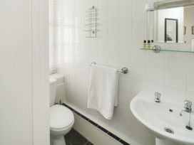 A bathroom with a toilet sink mirror towel rack and toiletries at The Link in Torquay