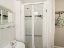 A bathroom with a shower cabin a sink a mirror and hangers on a rack at The Link in Torquay