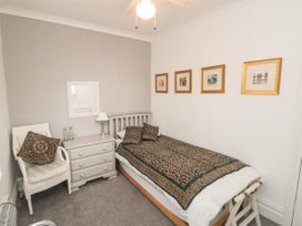 A bedroom with a single bed a bedside table a chair and framed pictures on the wall at The Link in Torquay