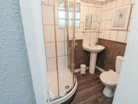 A bathroom with a corner shower, pedestal sink, toilet, mirror, and artwork on the wall at The Link in Torquay