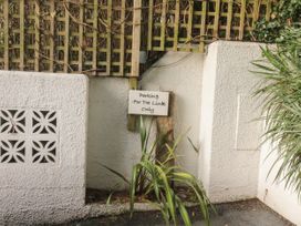 A white textured wall with a wooden lattice and a small sign reading Parking For The Link only at The Link in Torquay