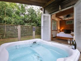 A hot tub with outdoor decking and a bed visible through a sliding door at 3 Southern Place Dobwalls