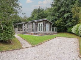 A cabin with a deck surrounded by grass and trees at 3 Southern Place in Dobwalls