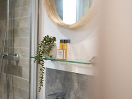 A bathroom with a mirror and shelf containing bottles and a plant at 24 Meadow Retreat in Dobwalls