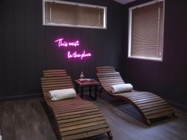 A wellness area with lounge chairs and a neon sign at 24 Meadow Retreat in Dobwalls