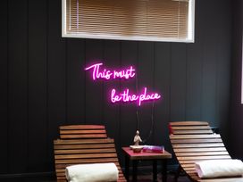 A neon sign with a message and wooden chairs at 24 Meadow Retreat in Dobwalls