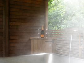 A hot tub with a wooden table and champagne at 24 Meadow Retreat in Dobwalls