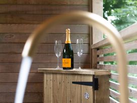 Champagne and glasses on a wooden cabinet in an outdoor area at 24 Meadow Retreat in Dobwalls