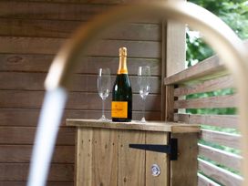 A wooden table with a champagne bottle and flutes at 24 Meadow Retreat in Dobwalls