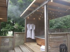 An outdoor bathroom with a bath tub and bathrobes at 24 Meadow Retreat in Dobwalls